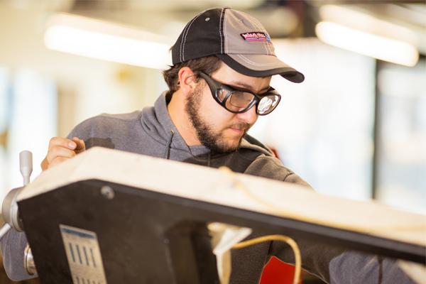 Student wearing safety goggles using mechanical engineering equipment